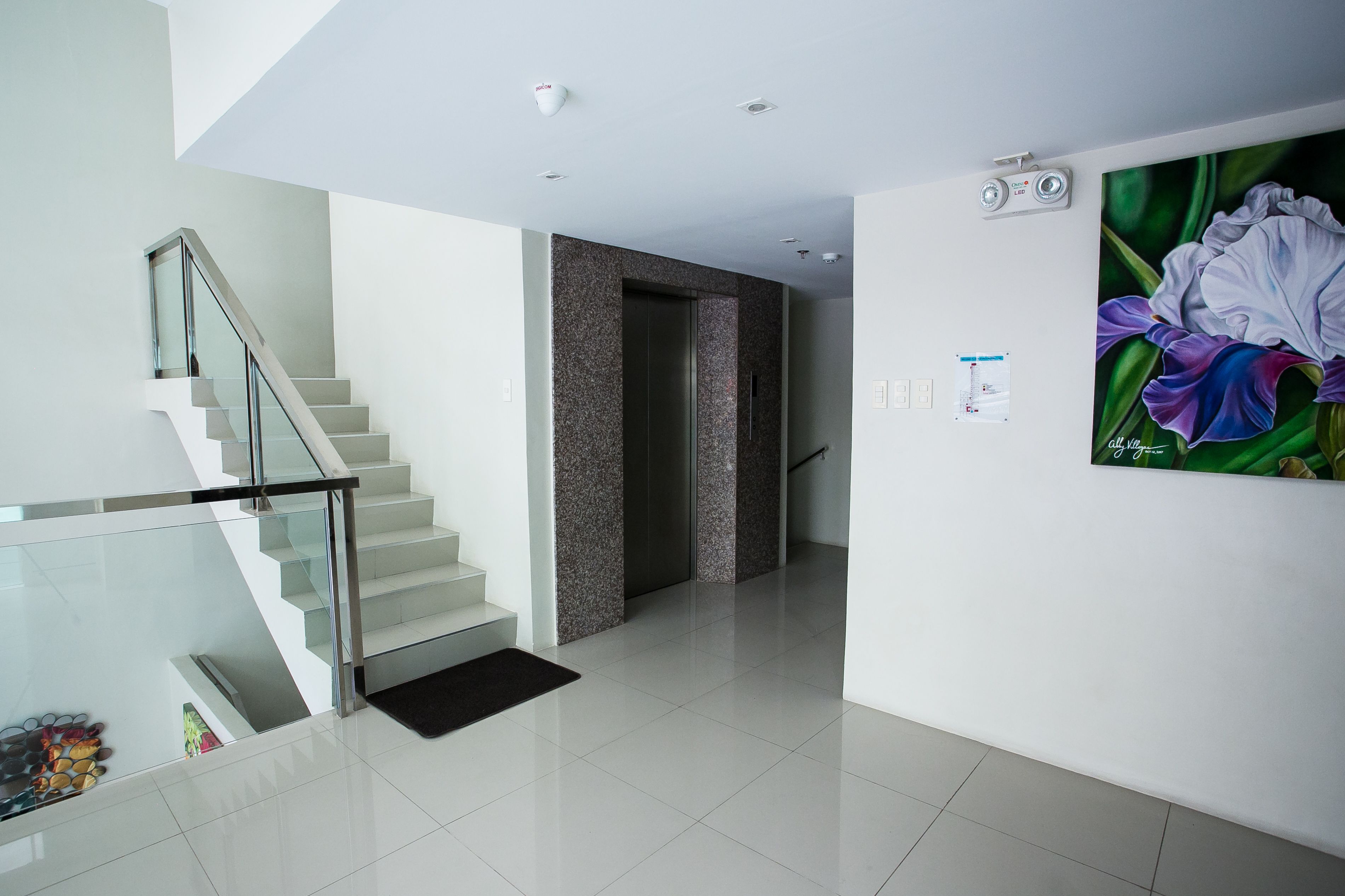 A modern interior with a glass staircase, a door leading to another room, and a wall-mounted security camera.