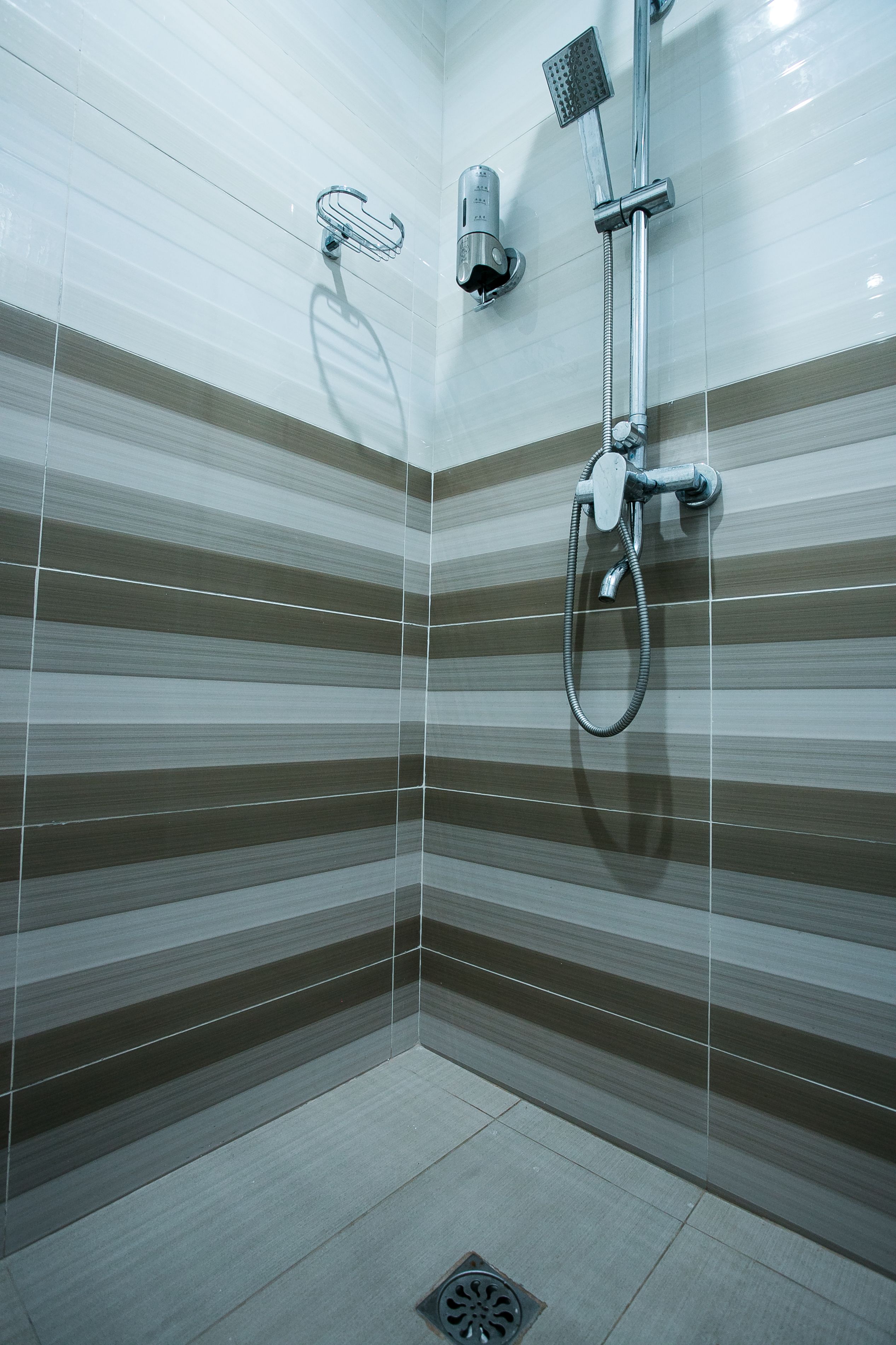 A shower with a handheld showerhead and a wall-mounted faucet.