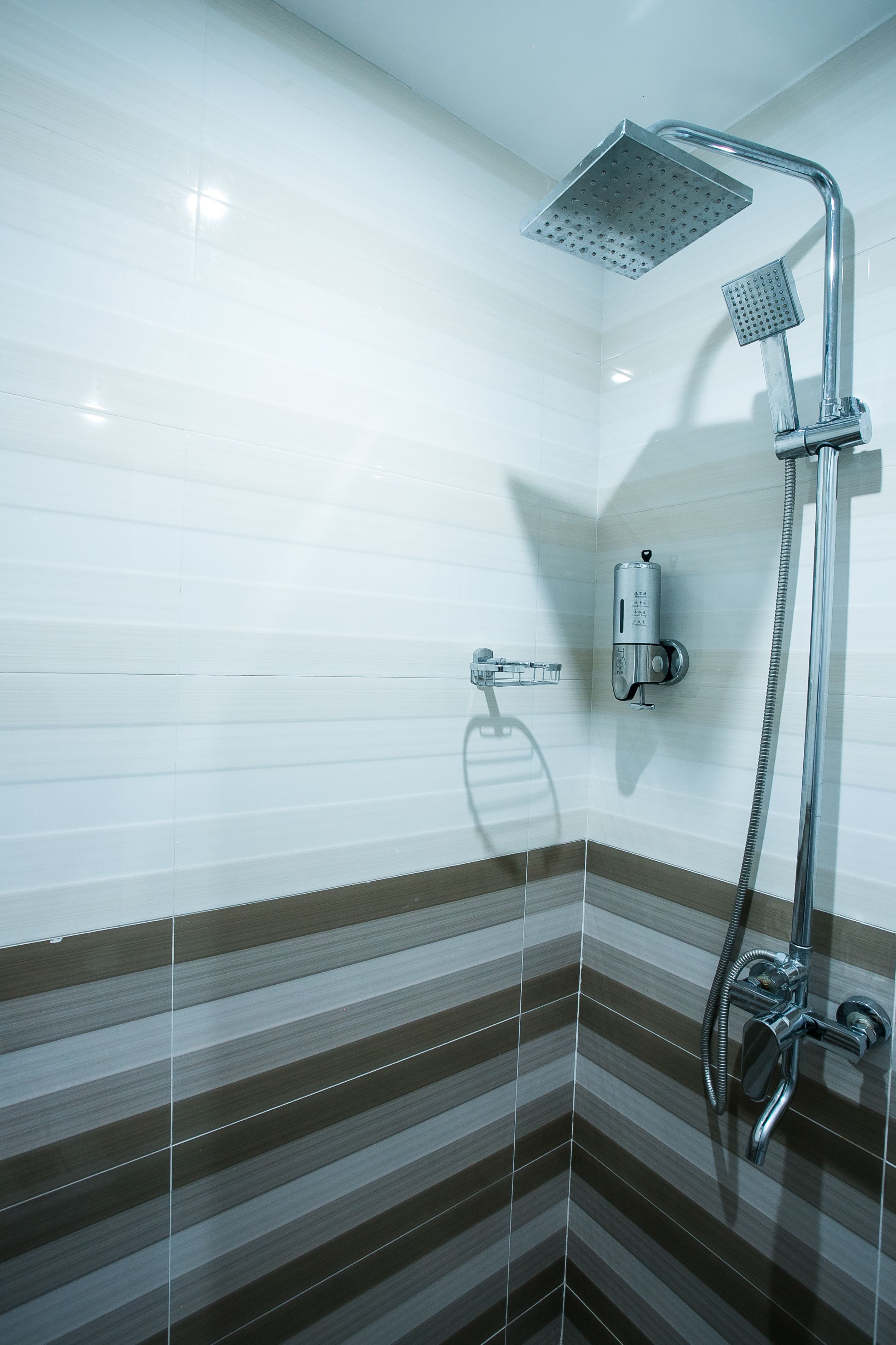 A shower area with a handheld showerhead and a wall-mounted control panel.