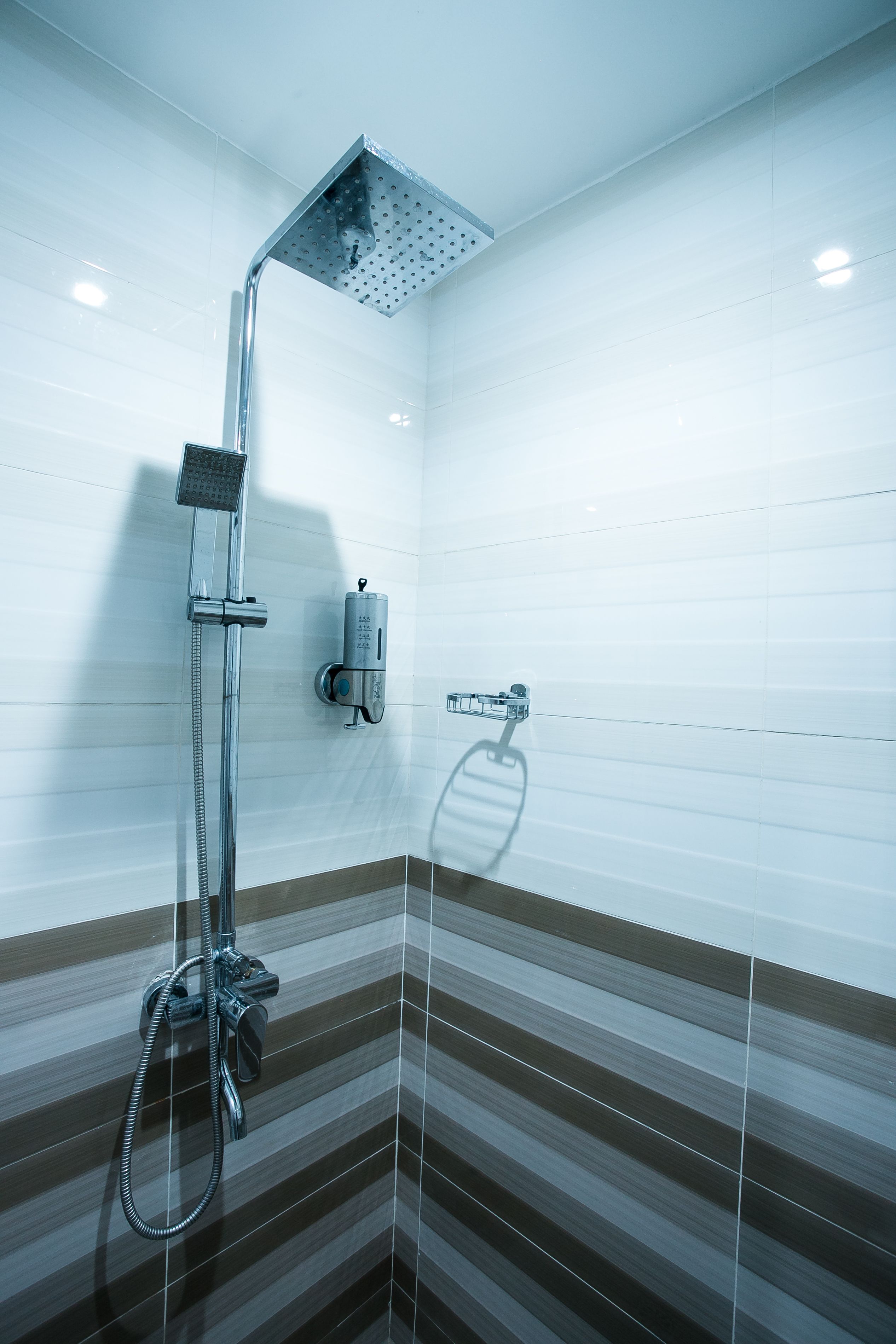 A shower with a handheld showerhead and a wall-mounted control panel.