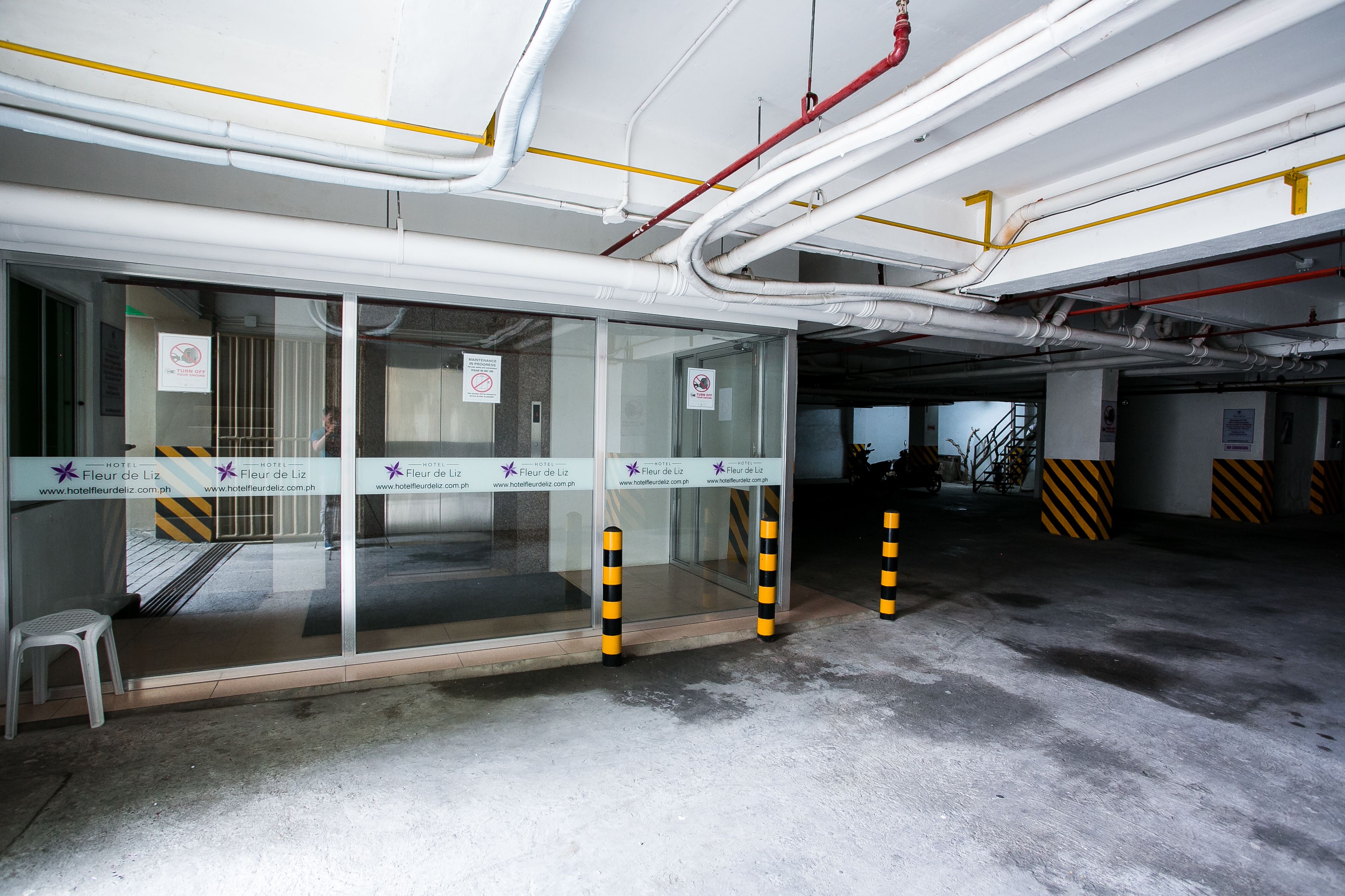 L’entrée d’un hôtel avec des portes vitrées, une rampe d’accès pour les personnes à mobilité réduite et un panneau indiquant qu’il est interdit de fumer.