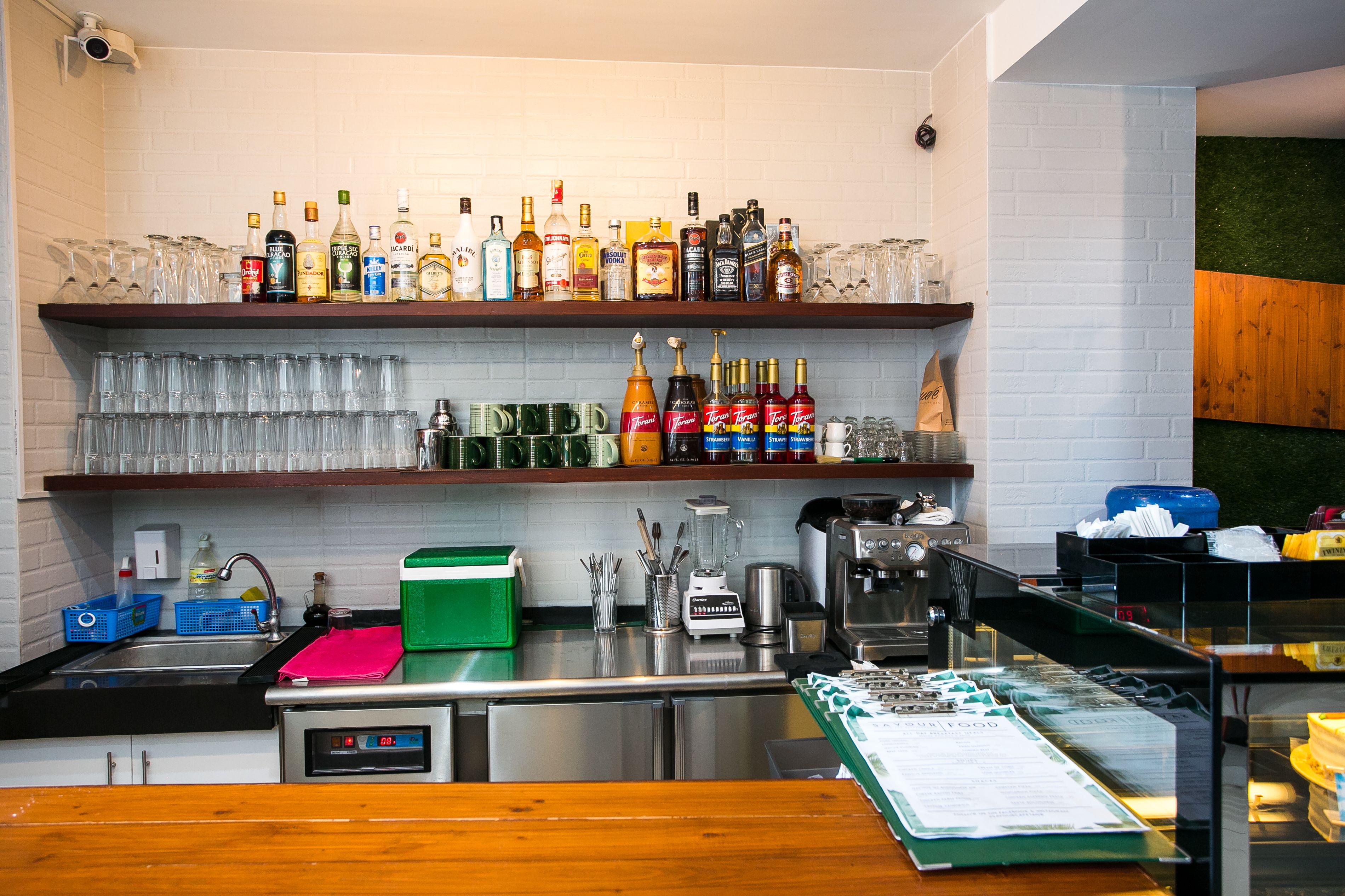 A bar area with shelves of liquor bottles, glasses, and a coffee machine.