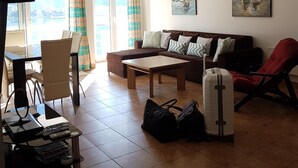 Un salon comprenant un canapé, une table basse, un téléviseur et un coin repas avec des chaises et une table.