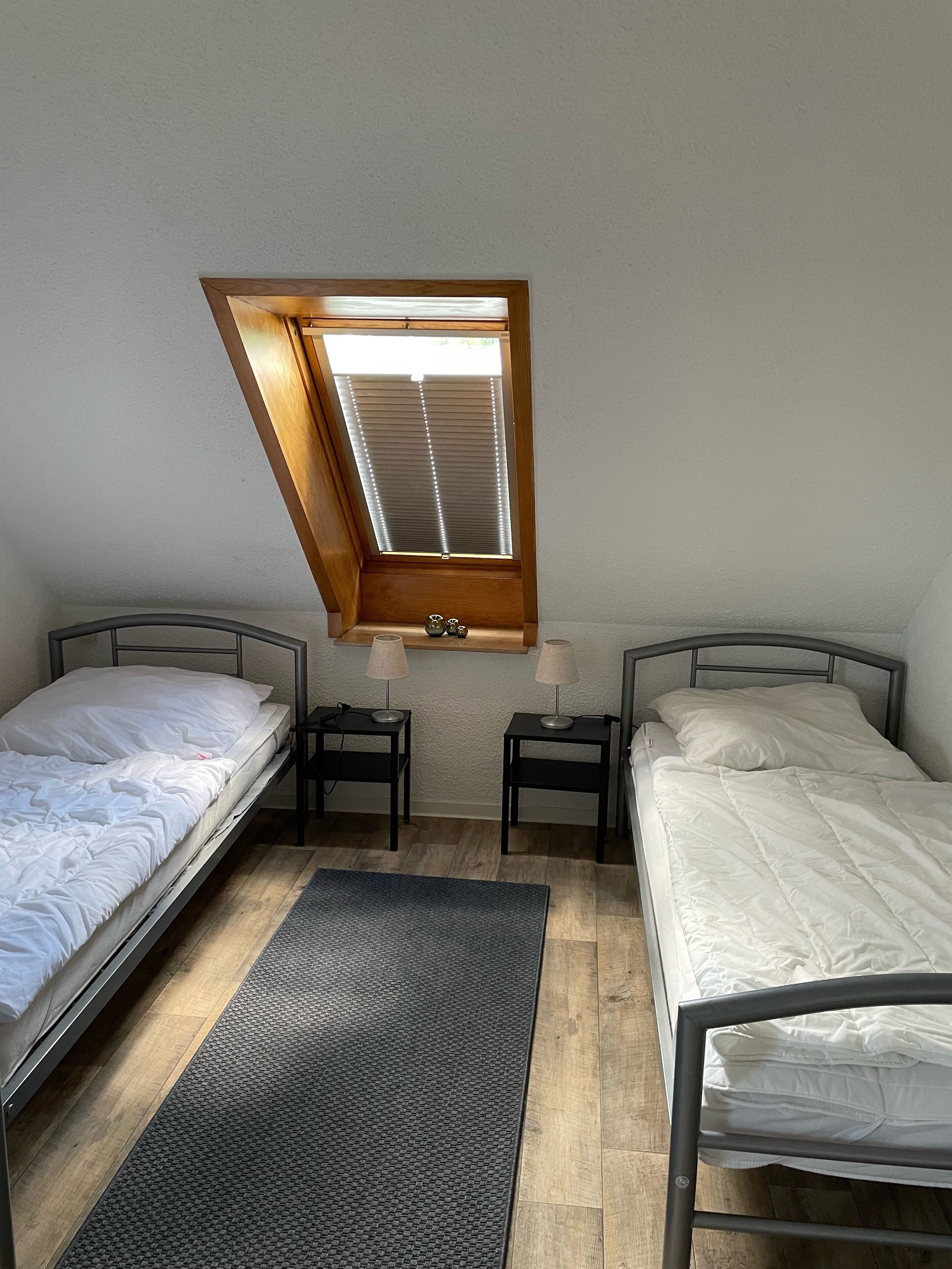 Un apartamento pequeño de una habitación con dos camas, un tragaluz y un estante con adornos.