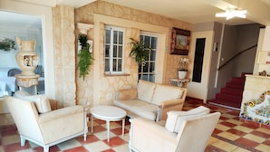 A living room with a stone wall, a sofa, a small table, and a staircase. - Hôtel Restaurant Le Commerce (Nogaro)