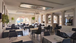 A spacious dining area with multiple tables and chairs, elegant chandeliers, and large mirrors. - Hôtel Restaurant Le Commerce (Nogaro)