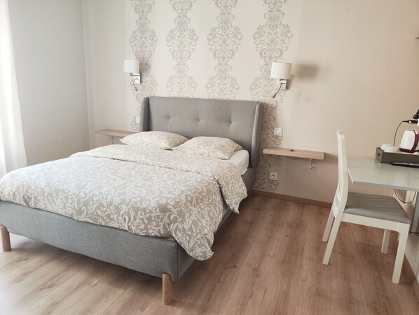 A neatly arranged bedroom with a bed, bedside tables, a desk, and a chair. - Hôtel Restaurant Le Commerce (Nogaro)