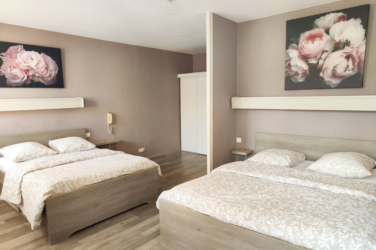 Habitación de hotel con dos camas, un teléfono, una mesita y un cuadro de flores.