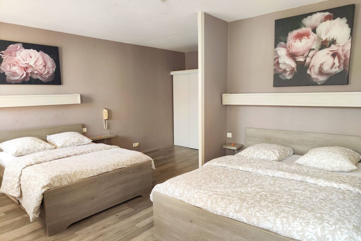 Un dormitorio moderno con dos camas, suelo de madera y un cuadro floral grande en la pared.