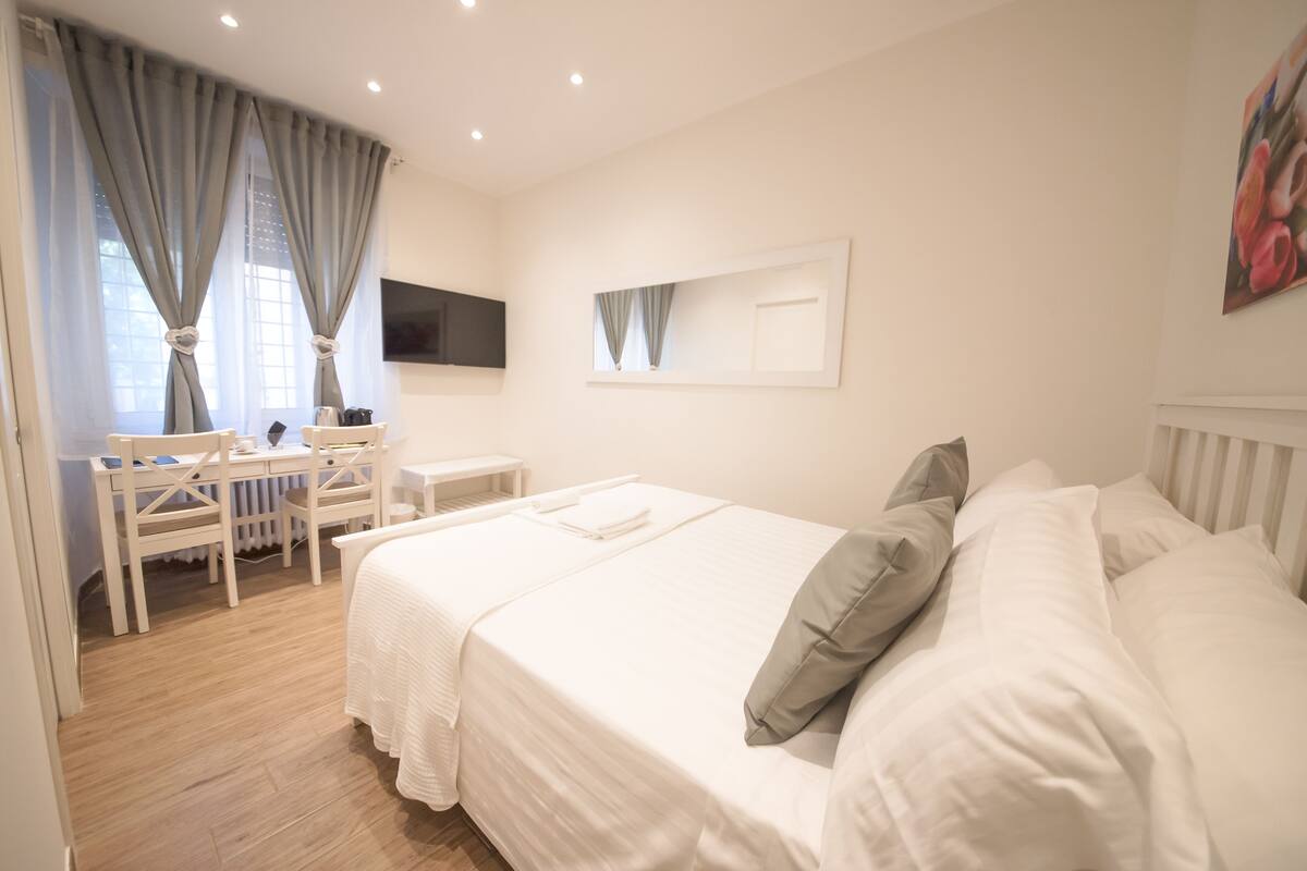 A bedroom with a bed, a desk, and a chair.
