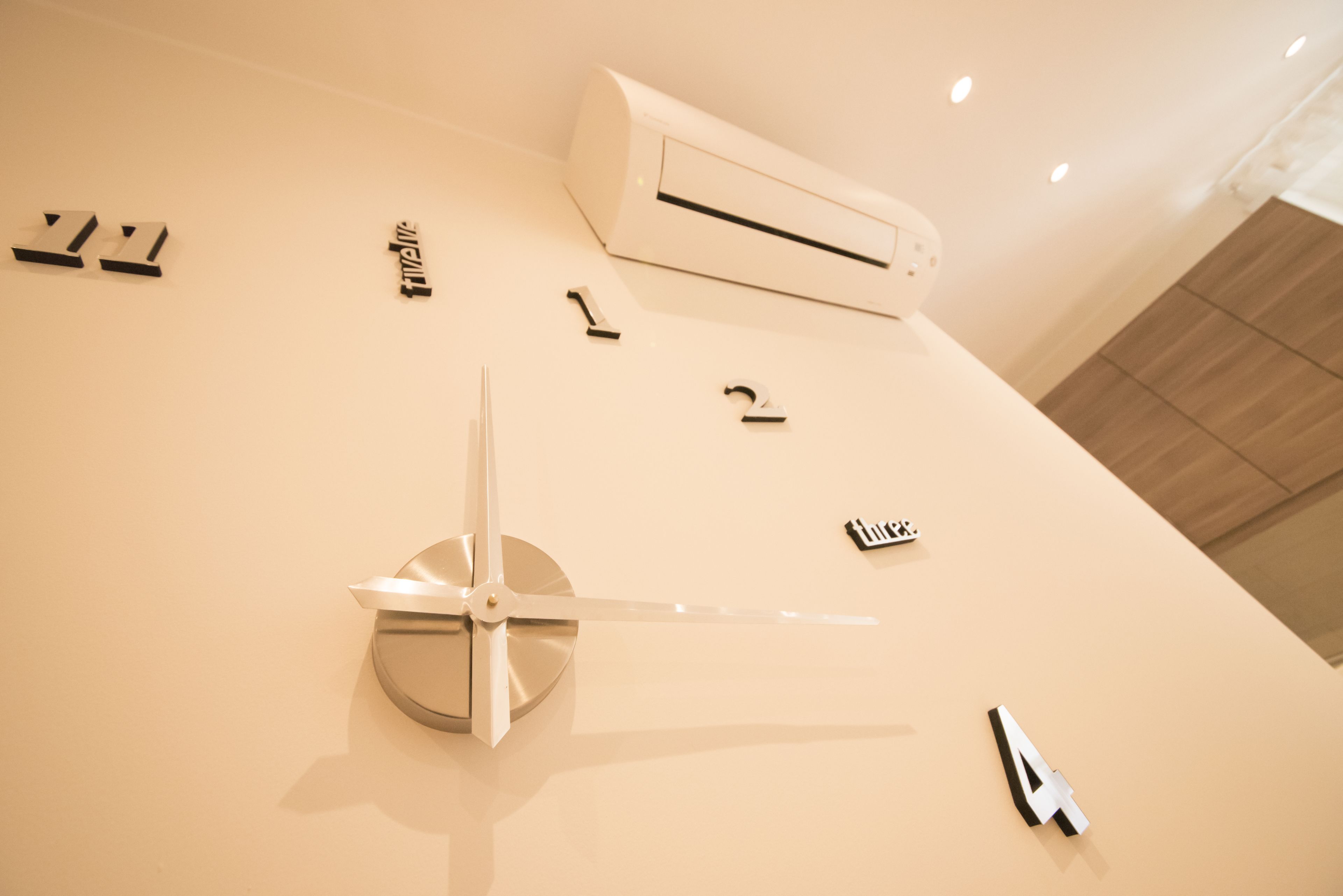 A minimalist wall with a ceiling fan, an air conditioning unit, and a few small, abstract wall decorations.
