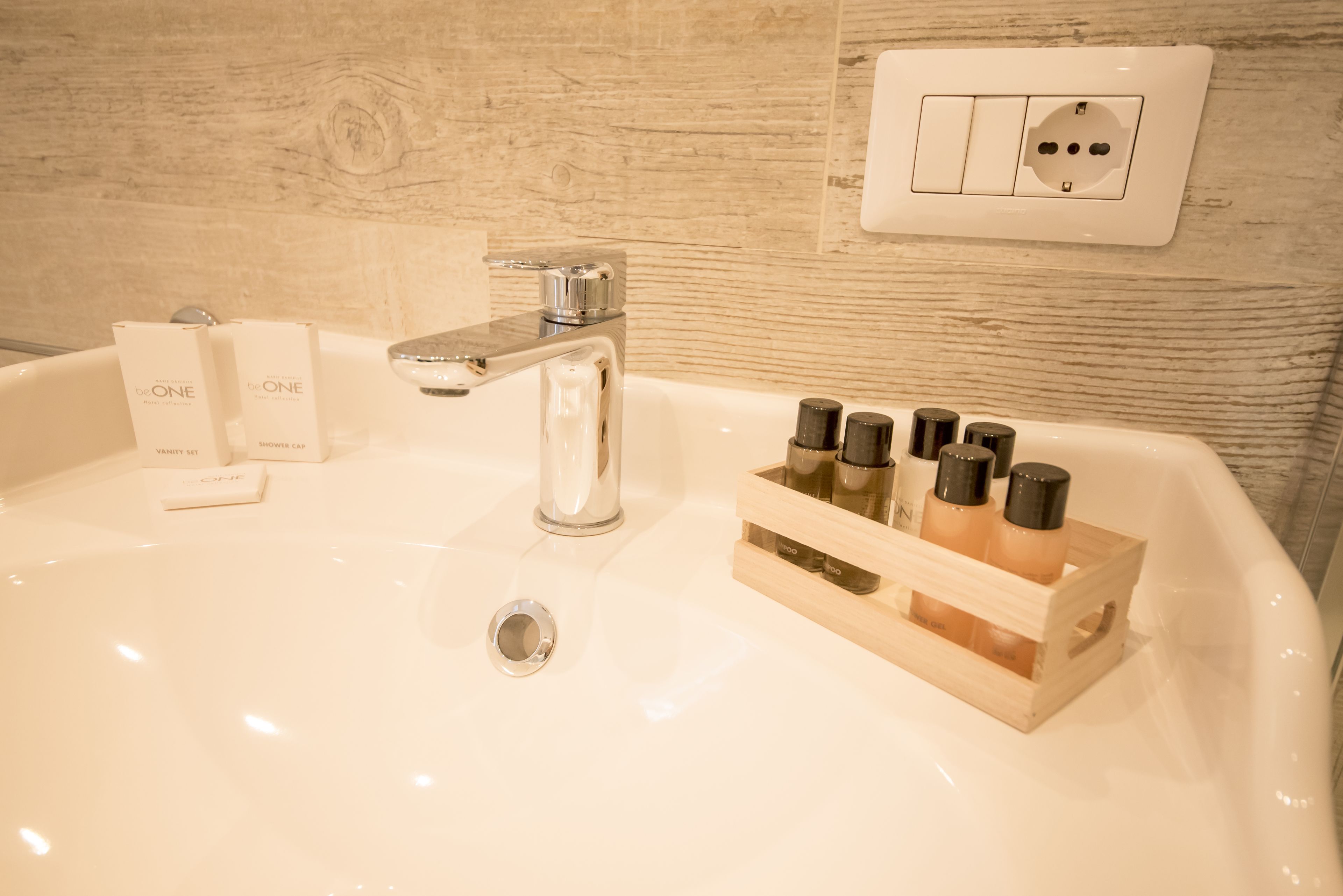 A bathroom sink with a chrome faucet, a wooden soap dish with bottles, and a vanity set.