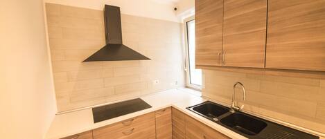 A modern kitchen with wooden cabinets, a black range hood, and a double sink.