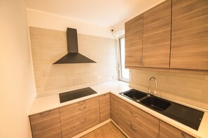 A modern kitchen with wooden cabinets, a black range hood, and a double sink. - BePlace Aventino (Rome)
