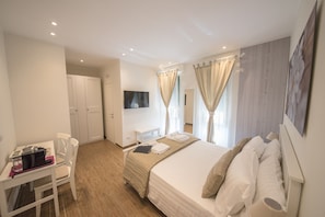 Une chambre d’hôtel avec un lit, un bureau, une chaise, une télévision et des rideaux.