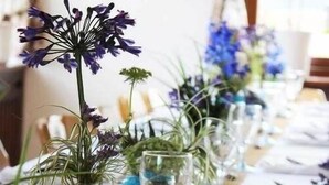 A table set with clear glassware and small vases containing purple flowers, arranged on a tablecloth. - Hotel - Landgasthof zum Pflug (Steinen)