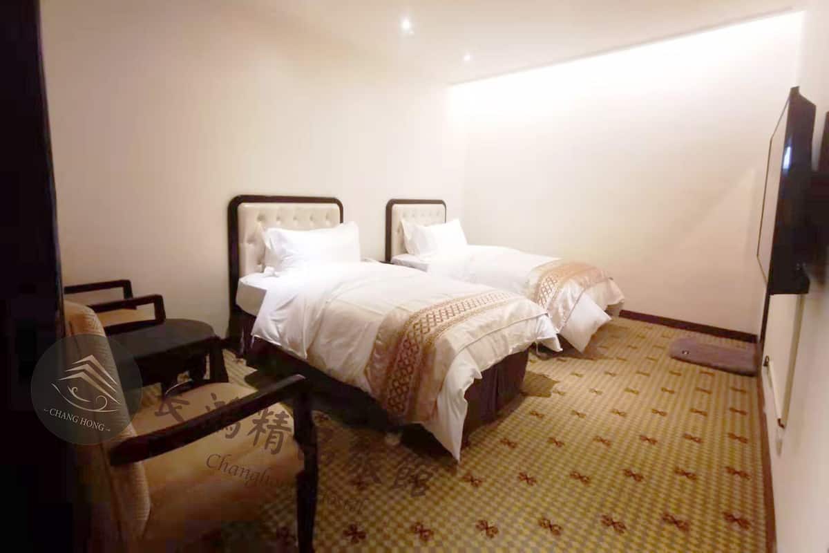 Ein Hotelzimmer mit zwei Betten, einem Schreibtisch und einem Sessel.