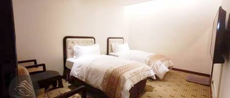 A hotel room with two beds, a desk, and a chair.