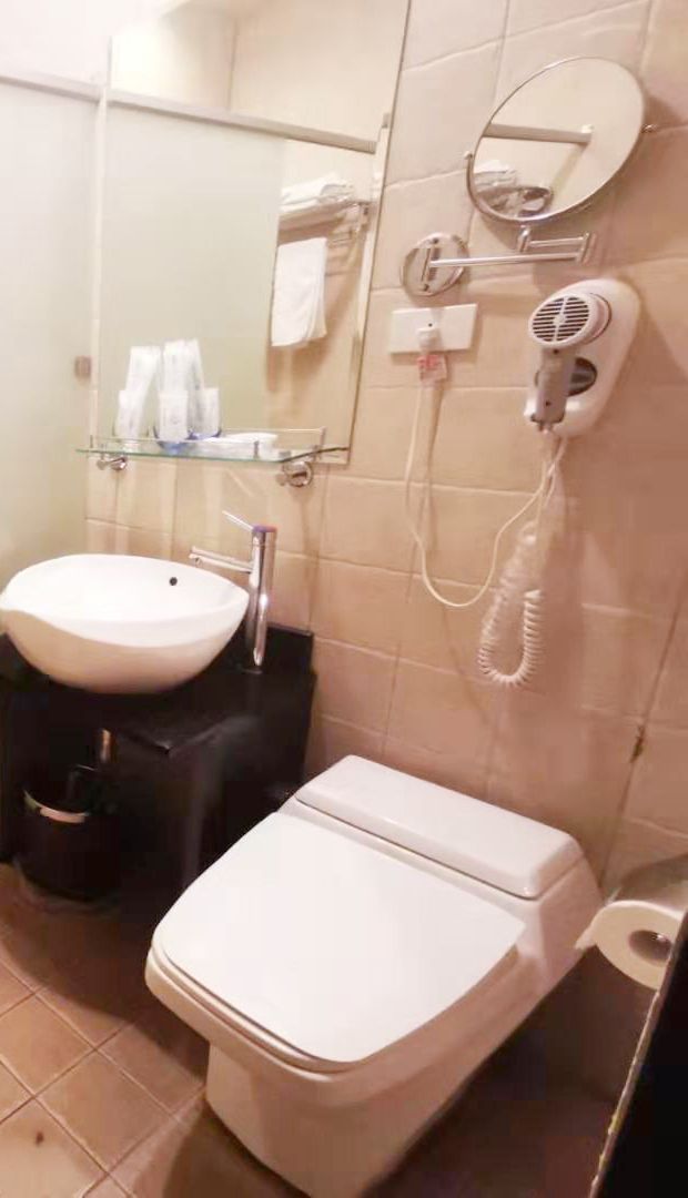 A bathroom with a white sink, a toilet, a hairdryer, and a mirror.