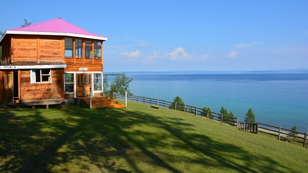 Une cabane en bois avec un toit rose, surplombant un lac.