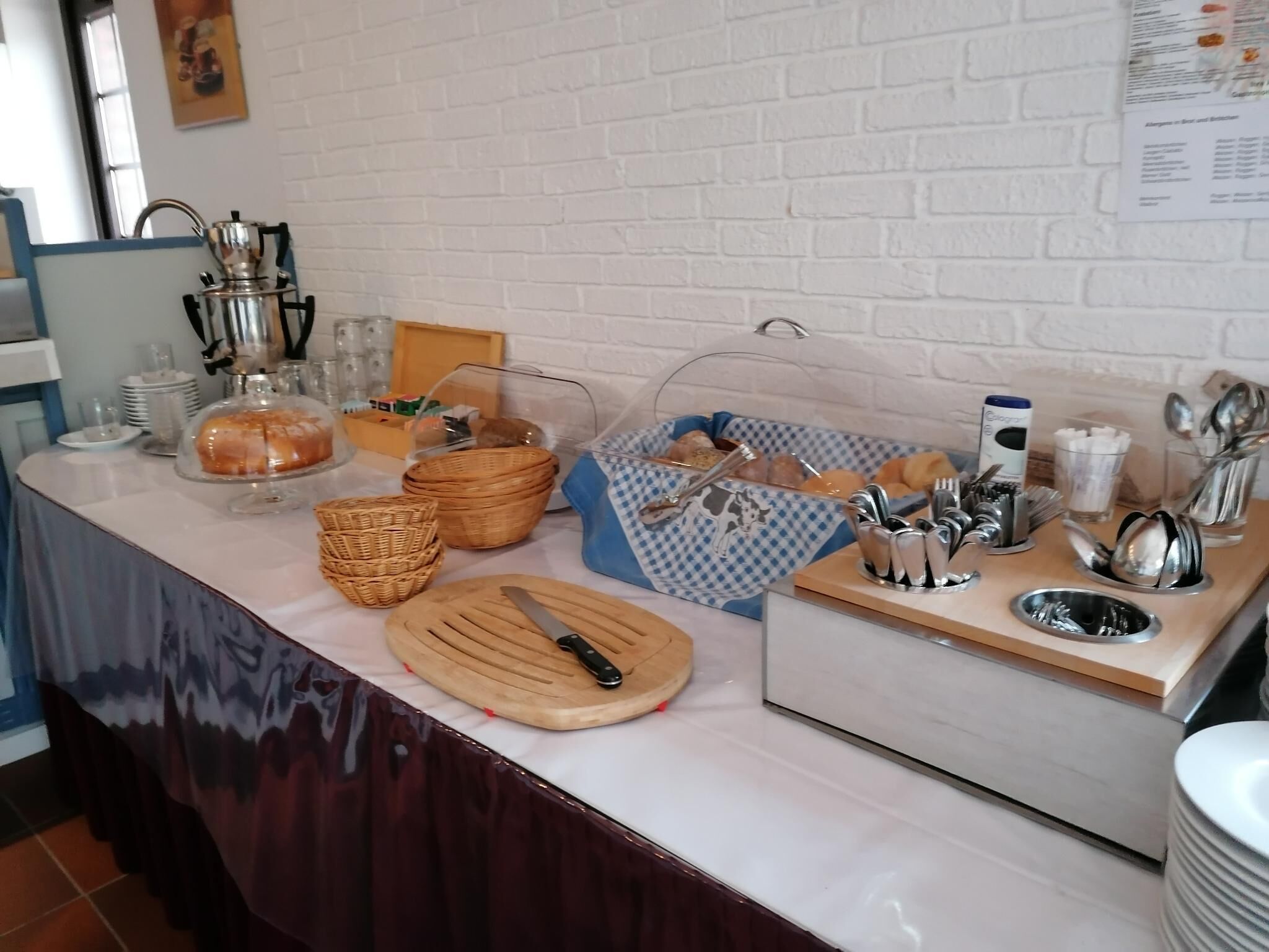 Ein reichhaltiges Frühstücksbuffet mit verschiedenen Speisen, Körben und Besteck auf einer Marmorplatte.