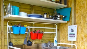 Una cocina compacta con un lavamanos, estantes y varios utensilios.