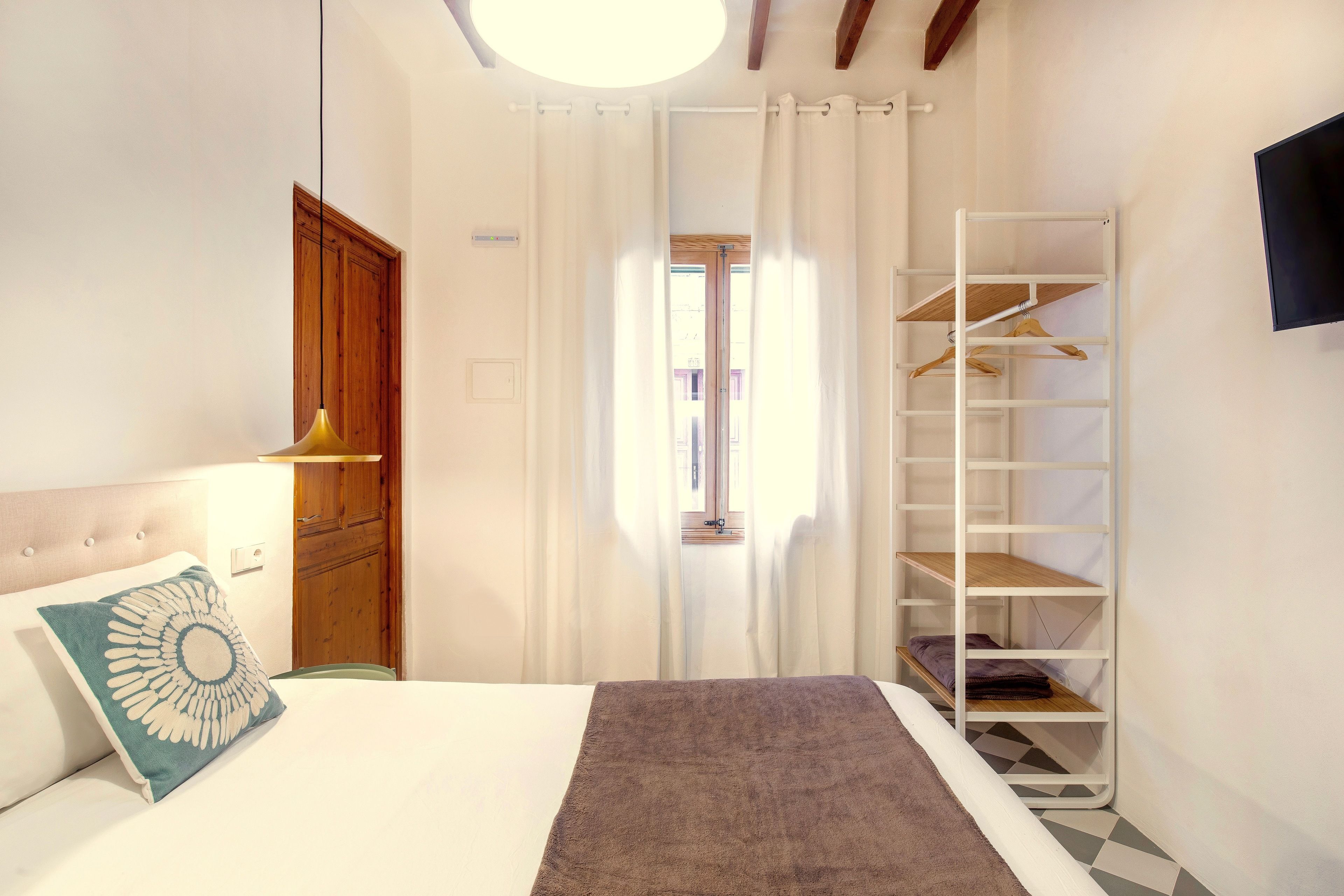 Quarto com cama, guarda-roupa, prateleira suspensa e televisão.
