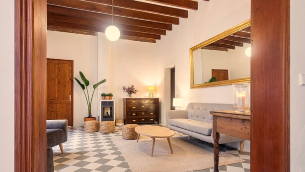 Una sala de estar con piso a cuadros, muebles de madera, un sofá, una mesa y un espejo.