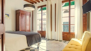 Un dormitorio con cama, sofá, armario de madera y ventana con cortinas.