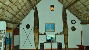 A room with a thatched roof, a television, speakers, and a painting on the wall. - Le Trou Normand (Antsiranana)