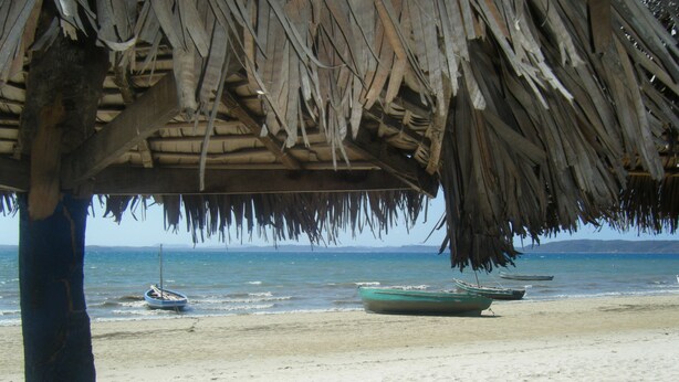 A beach with a thatched roof structure, a sandy shore, and a calm sea. - Le Trou Normand (Antsiranana)