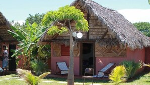 A pool area with a thatched-roof hut, lounge chairs, and palm trees. - Le Trou Normand (Antsiranana)