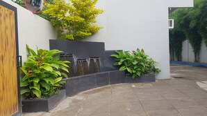 Un cortile con un elemento d'acqua, piante in vaso e una porta in legno.