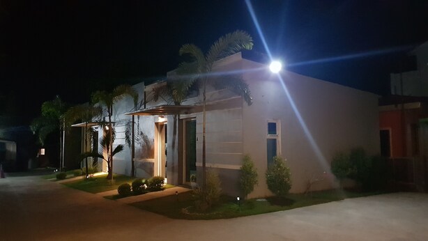 Un edificio moderno con un ingresso ben illuminato, circondato da palme e un vialetto lastricato.