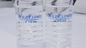 Due bottiglie d'acqua del Wild Flower Inn su un letto.