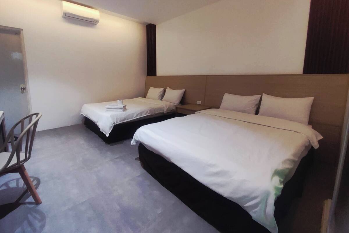 A hotel room with two single beds, a desk, and a chair.