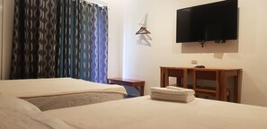 Ein Hotelzimmer mit zwei Betten, einem an der Wand montierten Fernseher, einem Holznachttisch und einem kleinen Holzstuhl.