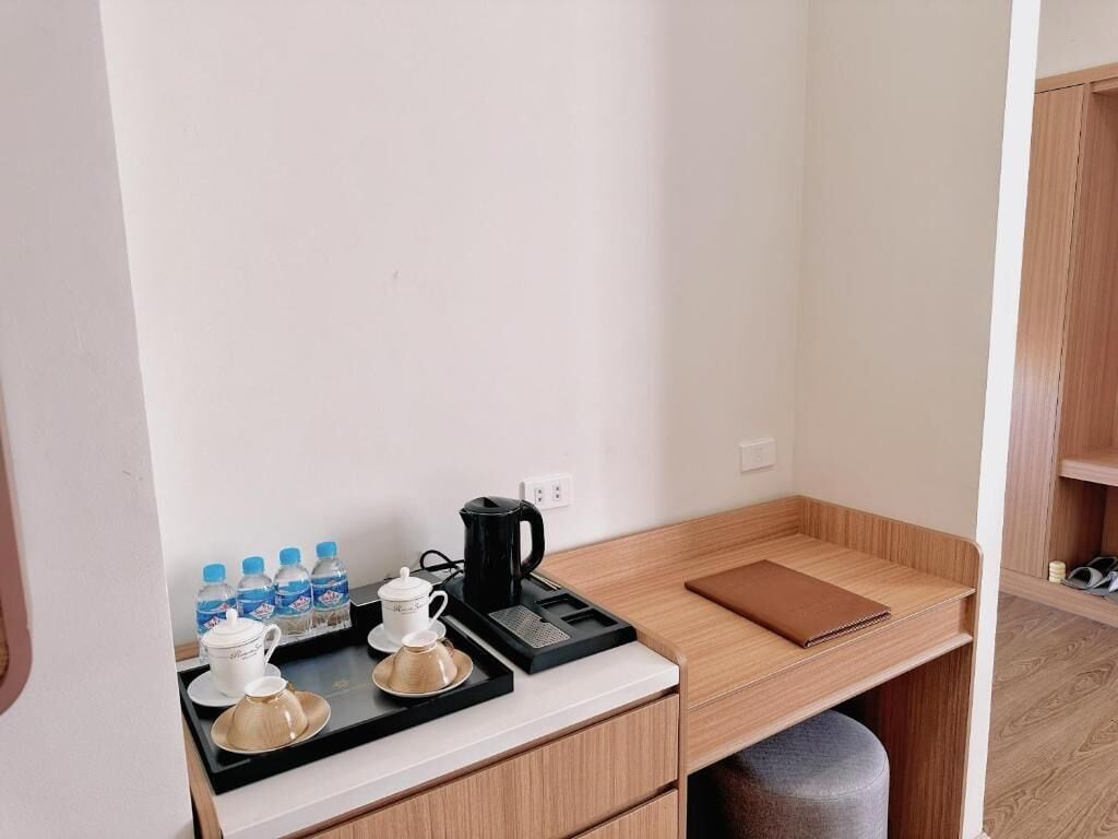 Una kitchenette compacta con cafetera, botellas de agua y una bandeja de tazas.