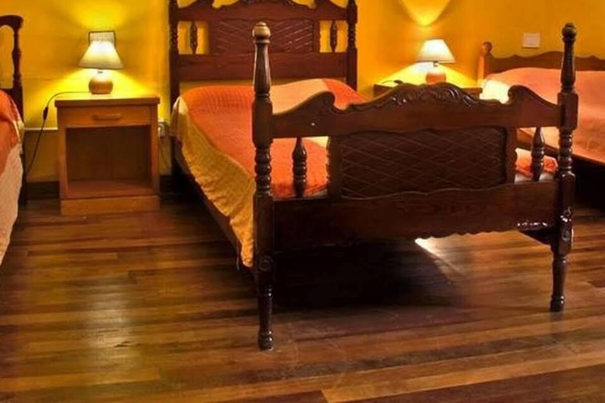 A hotel room with a wooden bed, two bedside tables with lamps, and two paintings on the walls.