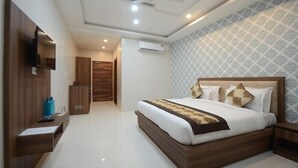 Ein modernes Hotelzimmer mit einem großen Bett, einem hölzernen Kopfteil, einem flachbildfernseher an der Wand, einem Deckenventilator und einer gemusterten Tapete.