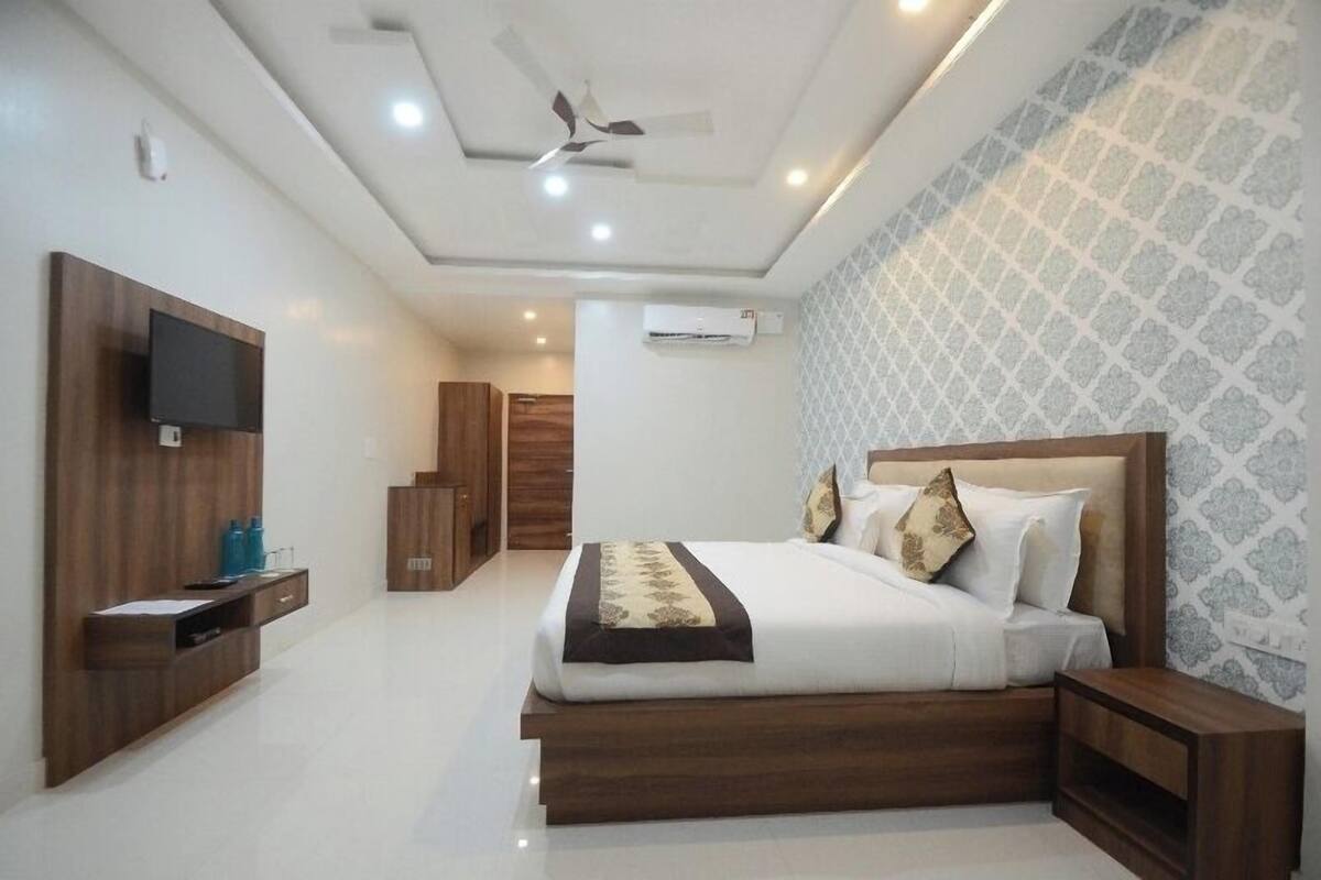 Una habitación de hotel moderna con cama, televisor, ventilador de techo y pared con diseño.