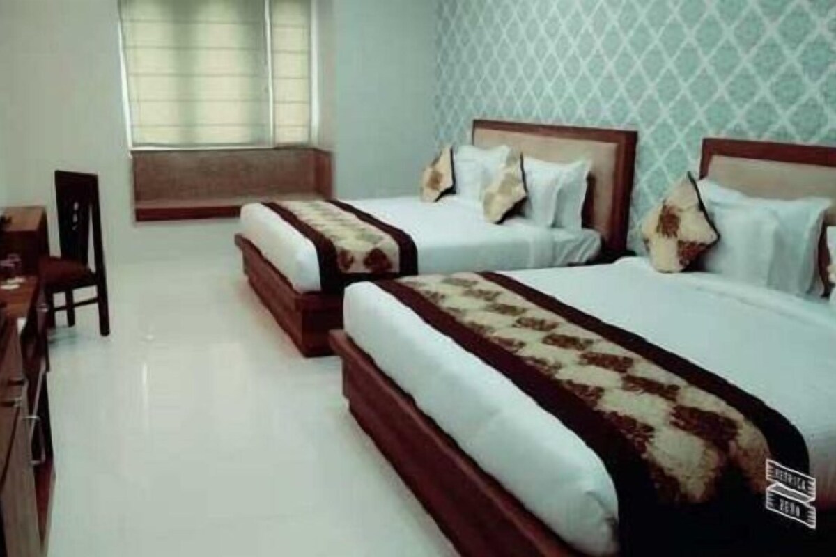 A hotel room with two beds, a desk, and a television.