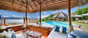 Une terrasse en bois avec une piscine, des chaises longues et un toit de chaume.