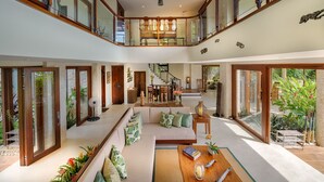 A spacious interior with a high ceiling, a central seating area, and large windows offering views of the outdoors.
