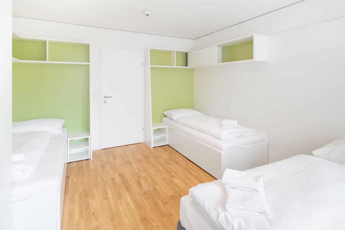 A bedroom with two beds, a wardrobe, and a door.