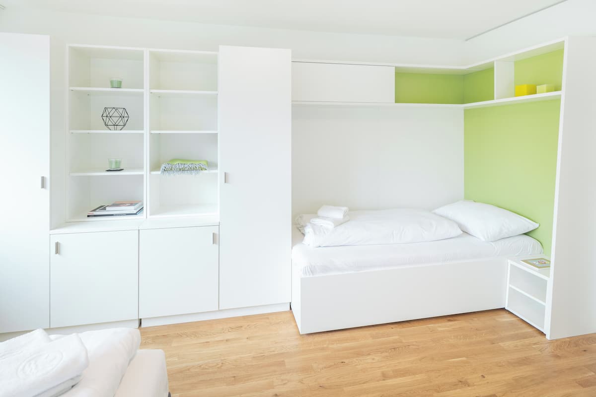 A compact bedroom with a bed, a wardrobe, and a small bedside table.