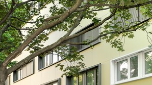 A multi-story building with large windows and a tree in front. - myNext - Hotel Leo (Vienna)