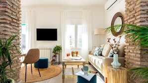 Ein modernes Wohnzimmer mit Fernseher, einer Couch, einem Couchtisch und einer Wand mit Ziegeln.