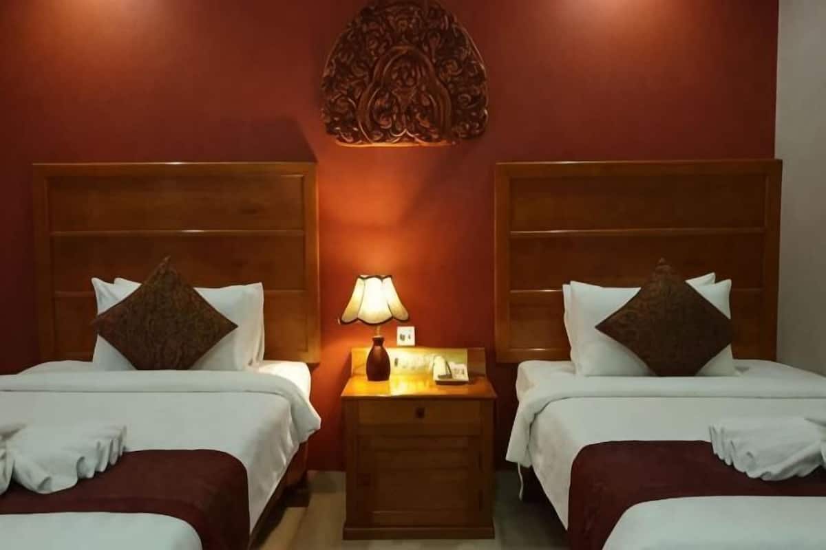Une chambre d’hôtel avec deux lits, une table de chevet avec une lampe et un élément décoratif mural.
