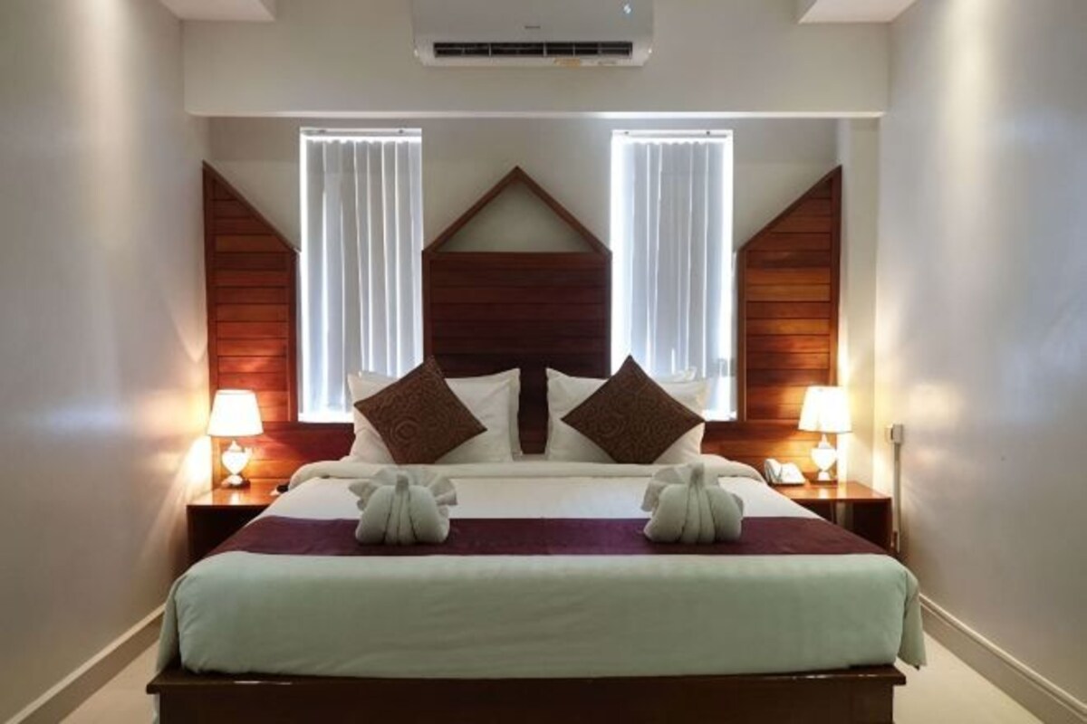 Una habitación de hotel con una cama grande, dos lámparas de noche y un cabecero de madera.